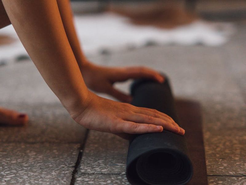 Close up of hands stretching on a black mat.