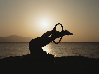 Person doing a stretching pose in silhouette.